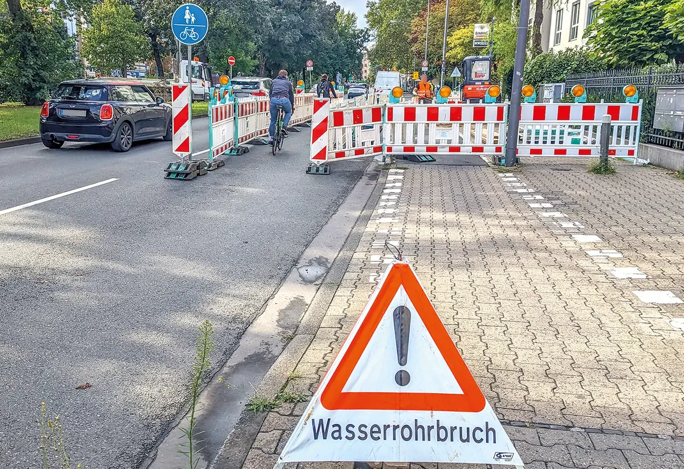 Ein Wasserrohrbruch auf dem Alleenring mit anschließender Sperrung des rechten Fahrstreifens (auch hier außerhalb der Ferien) sorgt nicht etwa für Chaos und endlose Autostaus, sondern wird stillschweigend akzeptiert. Sogar mit gut nutzbarem Notweg für den Rad- und Fußverkehr, wie er in den Richtlinien für Radverkehr an Baustellen vorgesehen ist! So ähnlich können wir uns hier eine dauerhafte Alternative zu dem buckeligen Hochbordradweg vorstellen.